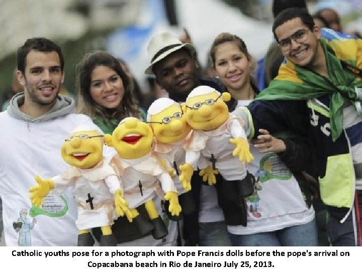 Catholic youths pose for a photograph with Pope Francis dolls before the pope's arrival