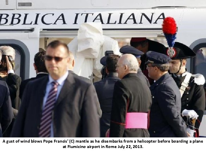 A gust of wind blows Pope Francis' (C) mantle as he disembarks from a