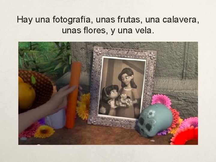 Hay una fotografía, unas frutas, una calavera, unas flores, y una vela. 