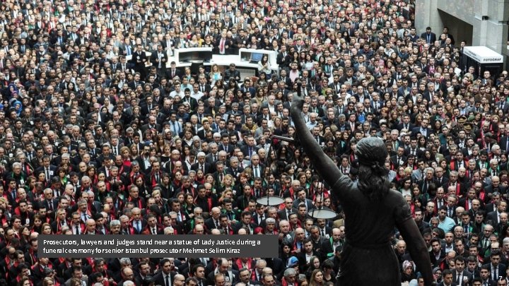 Prosecutors, lawyers and judges stand near a statue of Lady Justice during a funeral