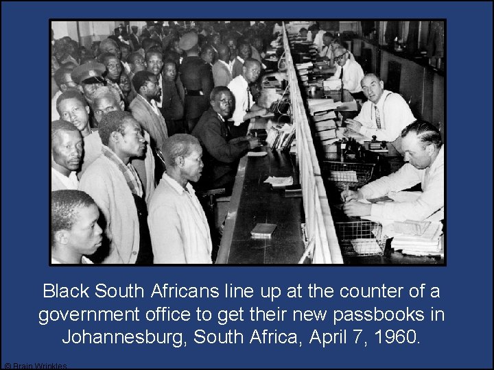 Black South Africans line up at the counter of a government office to get