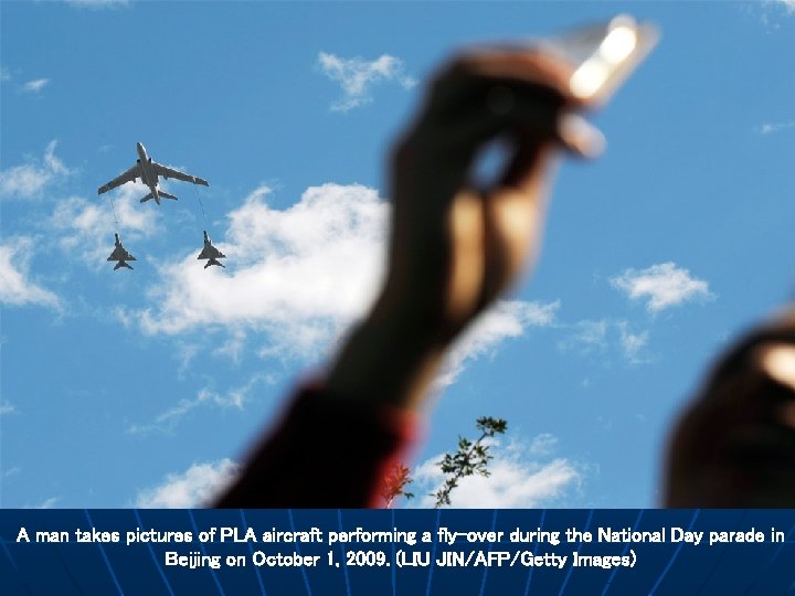 A man takes pictures of PLA aircraft performing a fly-over during the National Day