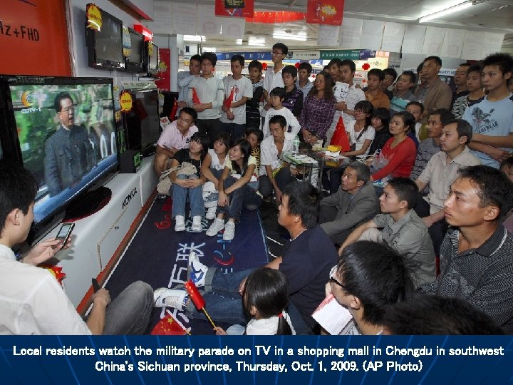 Local residents watch the military parade on TV in a shopping mall in Chengdu
