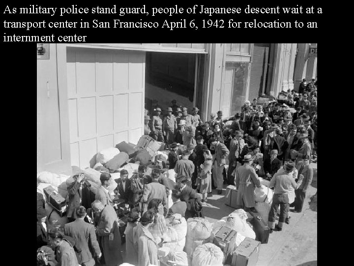 As military police stand guard, people of Japanese descent wait at a transport center