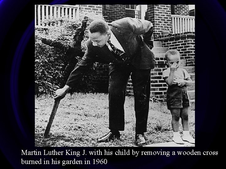 Martin Luther King J. with his child by removing a wooden cross burned in