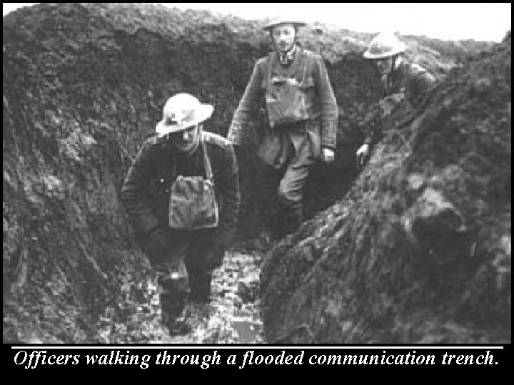 Officers walking through a flooded communication trench. 