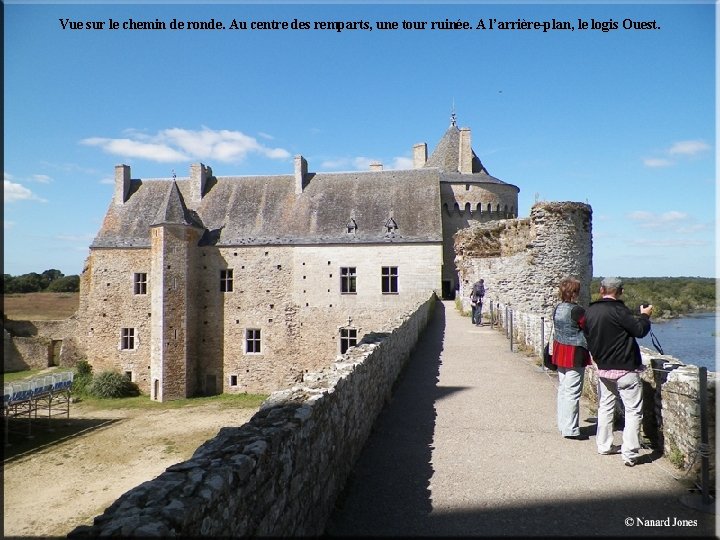 Vue sur le chemin de ronde. Au centre des remparts, une tour ruinée. A