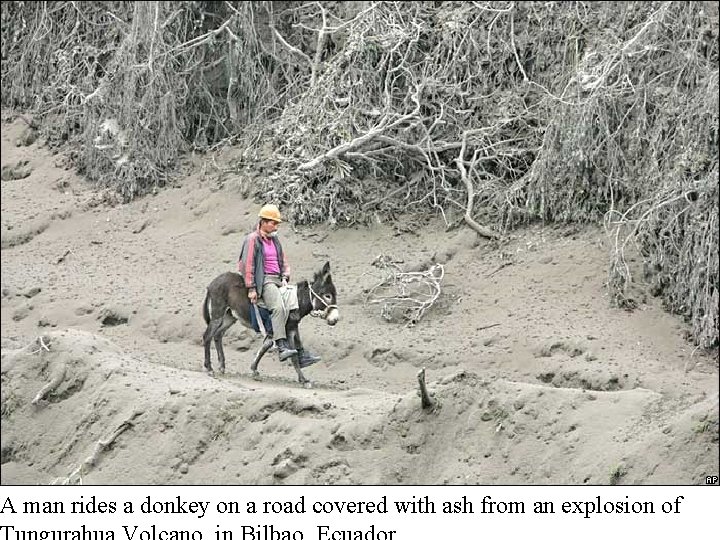 A man rides a donkey on a road covered with ash from an explosion