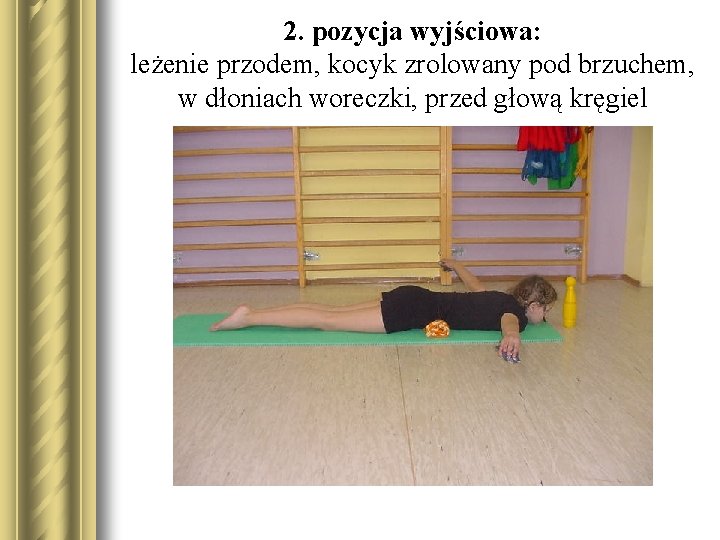 2. pozycja wyjściowa: leżenie przodem, kocyk zrolowany pod brzuchem, w dłoniach woreczki, przed głową