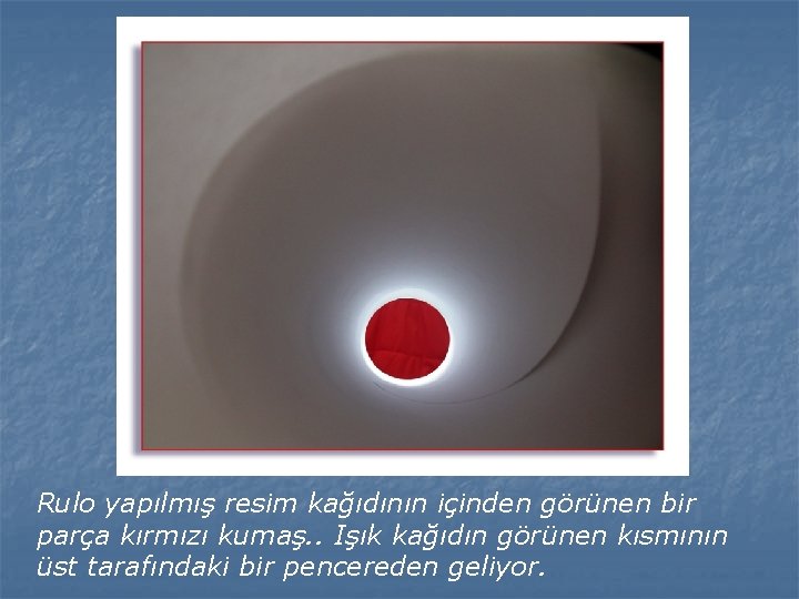 Rulo yapılmış resim kağıdının içinden görünen bir parça kırmızı kumaş. . Işık kağıdın görünen