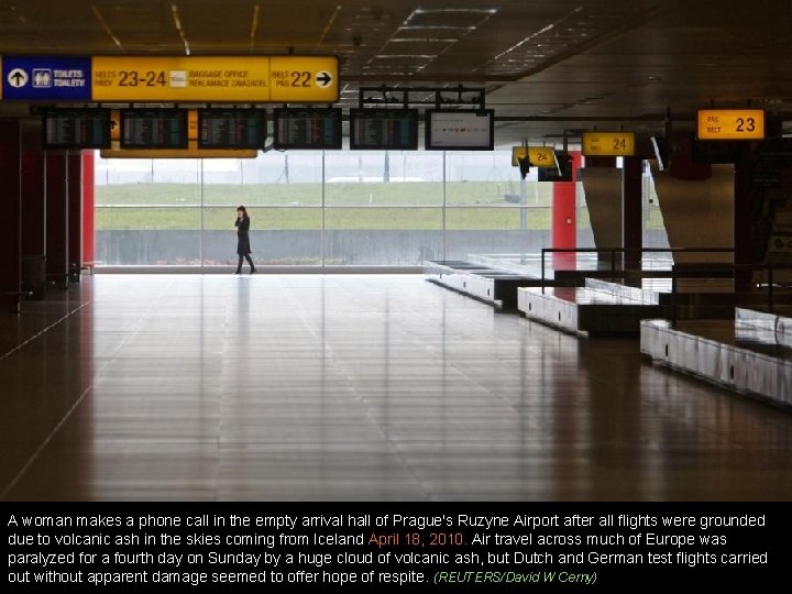 A woman makes a phone call in the empty arrival hall of Prague's Ruzyne