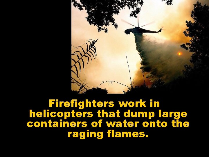 Firefighters work in helicopters that dump large containers of water onto the raging flames.