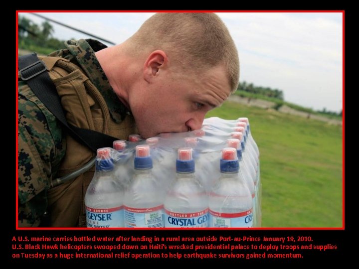 A U. S. marine carries bottled water after landing in a rural area outside