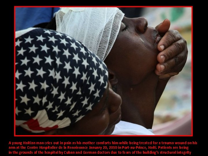 A young Haitian man cries out in pain as his mother comforts him while