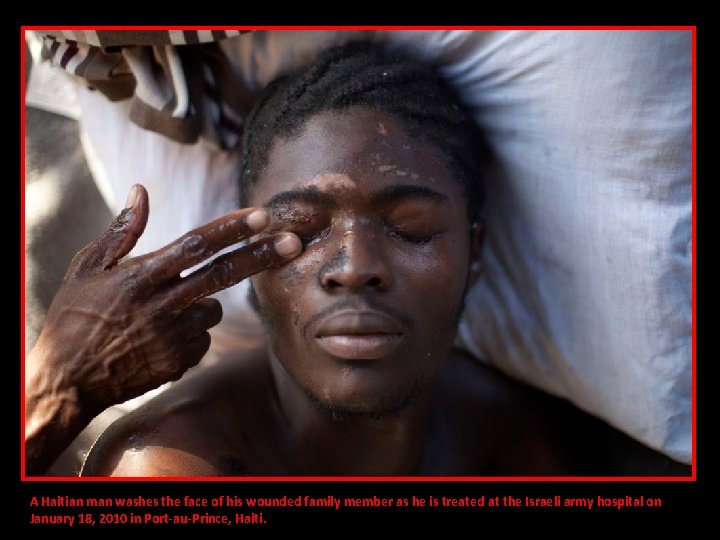 A Haitian man washes the face of his wounded family member as he is