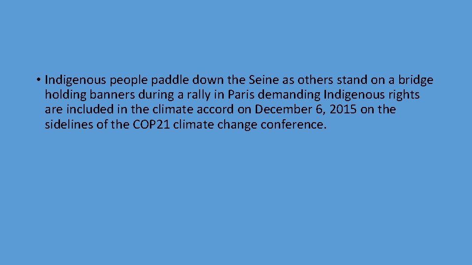  • Indigenous people paddle down the Seine as others stand on a bridge