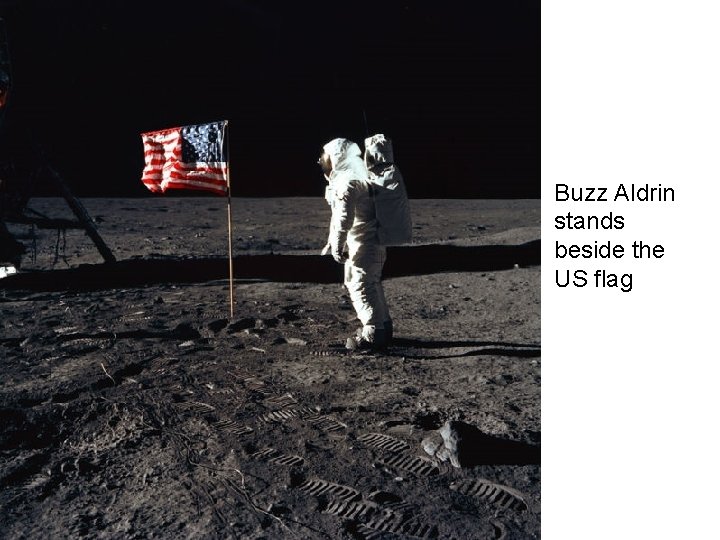 Buzz Aldrin stands beside the US flag 