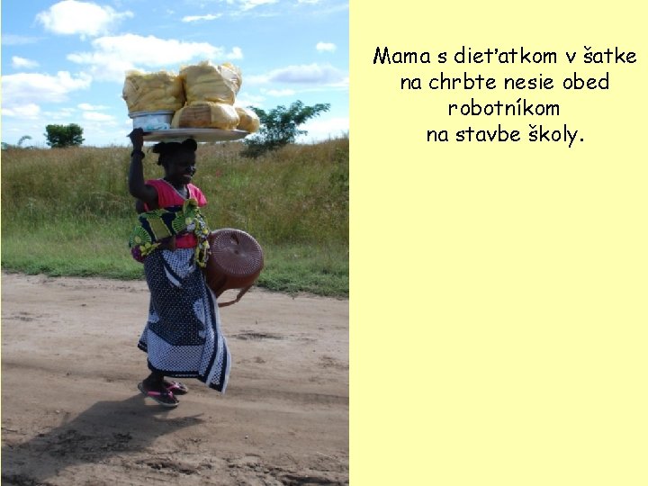 Mama s dieťatkom v šatke na chrbte nesie obed robotníkom na stavbe školy. 