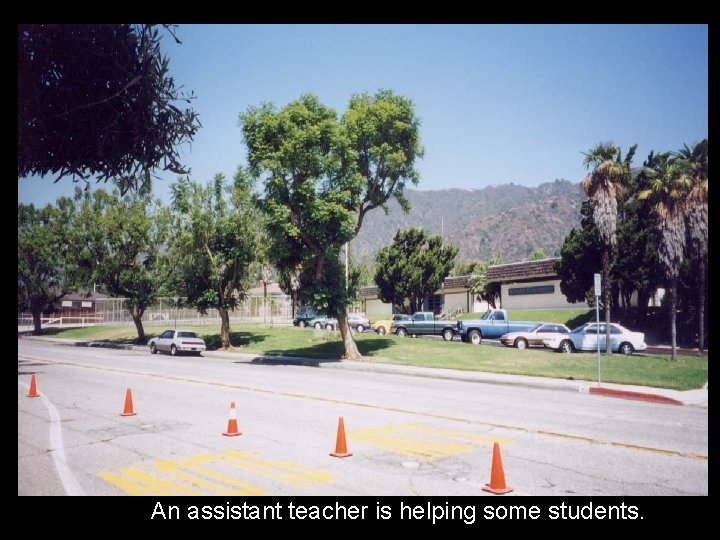 An assistant teacher is helping some students. 