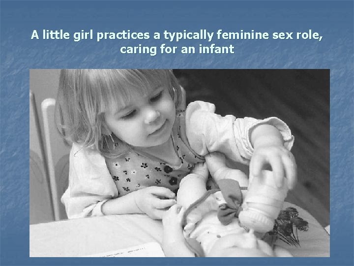 A little girl practices a typically feminine sex role, caring for an infant 