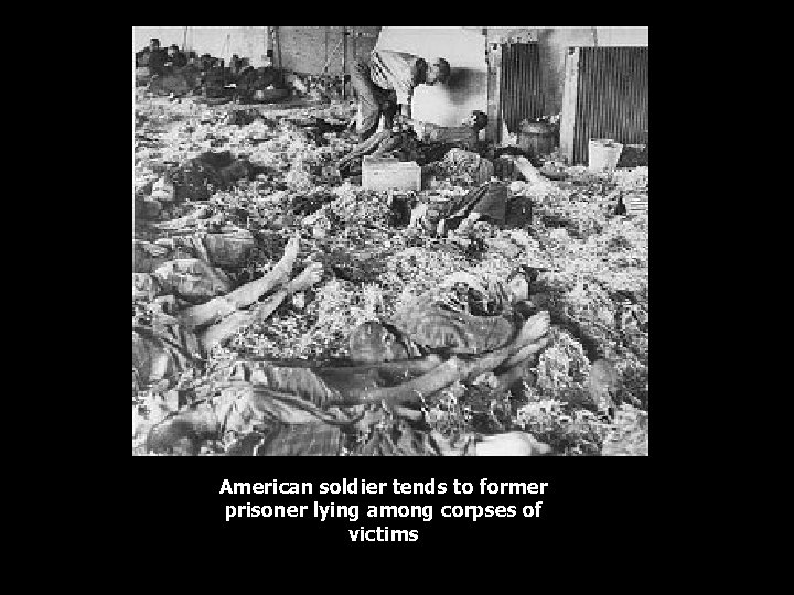 American soldier tends to former prisoner lying among corpses of victims 