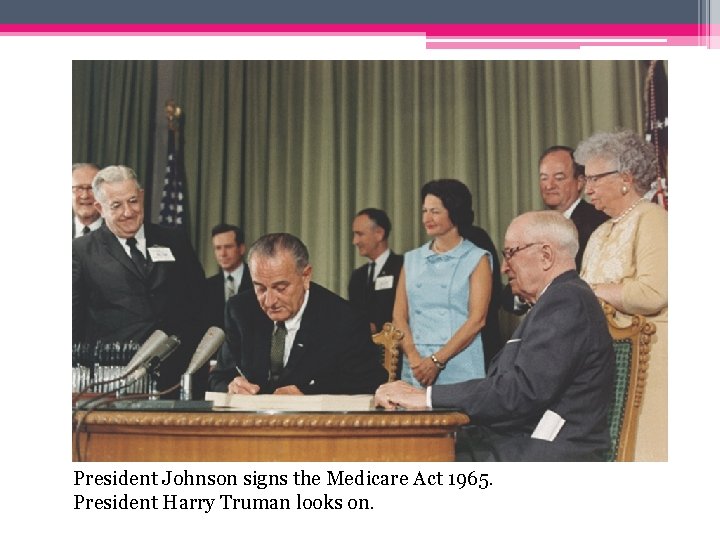 President Johnson signs the Medicare Act 1965. President Harry Truman looks on. 