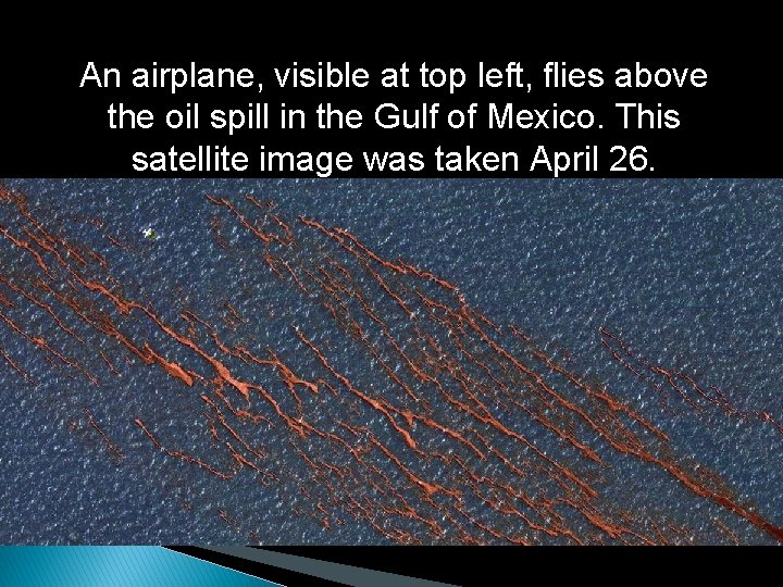 An airplane, visible at top left, flies above the oil spill in the Gulf