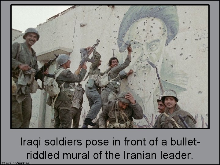 Iraqi soldiers pose in front of a bulletriddled mural of the Iranian leader. ©