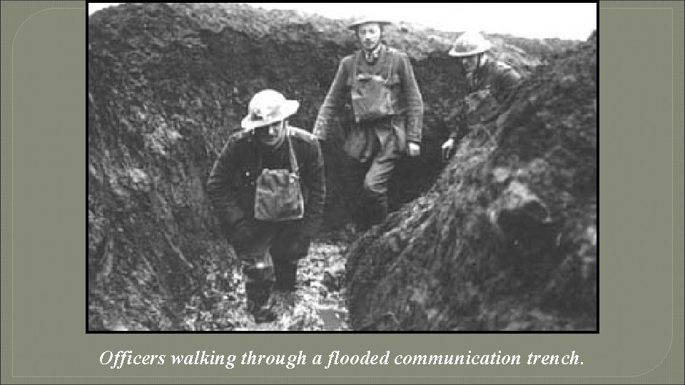 Officers walking through a flooded communication trench. 
