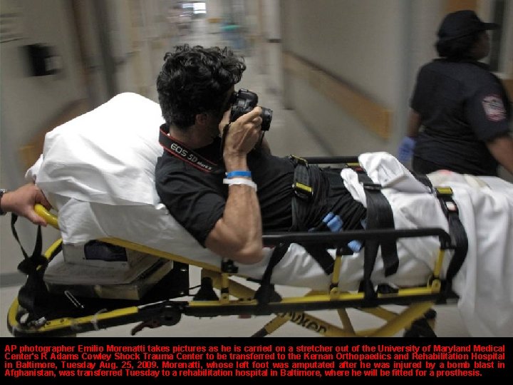 AP photographer Emilio Morenatti takes pictures as he is carried on a stretcher out