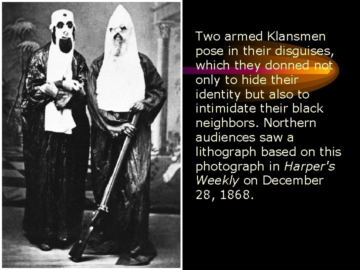 Two armed Klansmen pose in their disguises, which they donned not only to hide