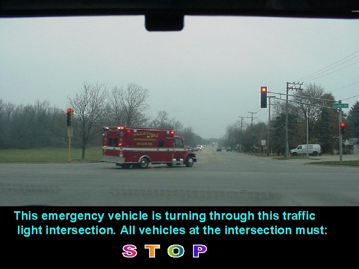 This emergency vehicle is turning through this traffic light intersection. All vehicles at the This emergency vehicle is turning through this traffic light intersection. All vehicles at the