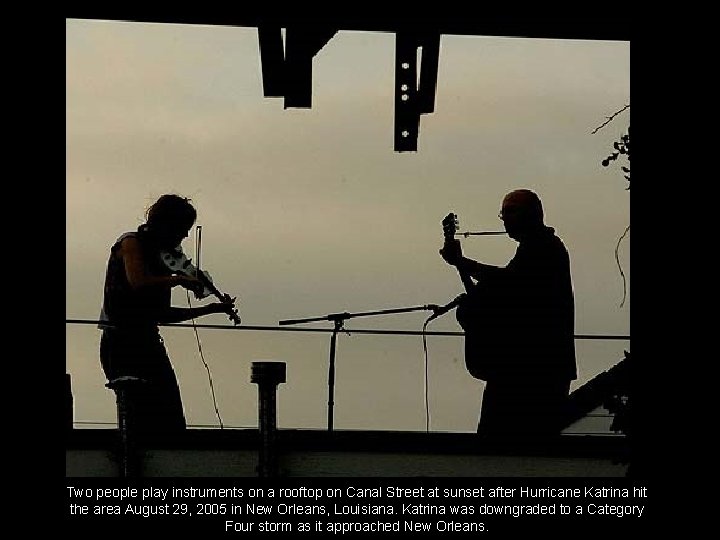 Two people play instruments on a rooftop on Canal Street at sunset after Hurricane