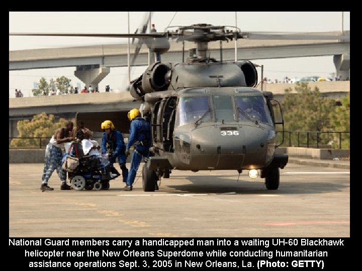 National Guard members carry a handicapped man into a waiting UH-60 Blackhawk helicopter near