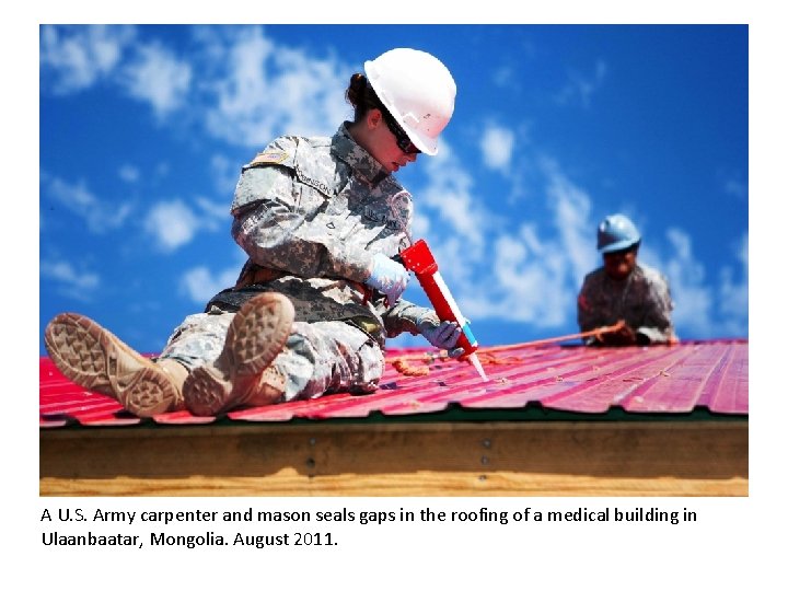 A U. S. Army carpenter and mason seals gaps in the roofing of a