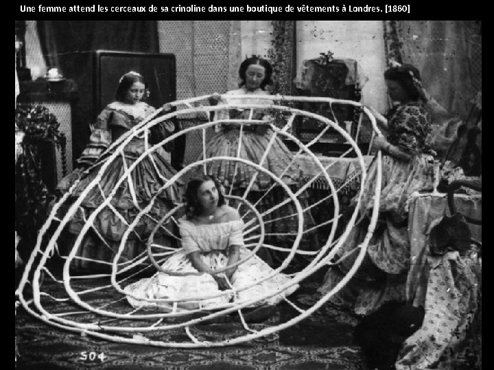 Une femme attend les cerceaux de sa crinoline dans une boutique de vêtements à