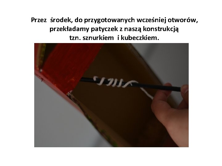 Przez środek, do przygotowanych wcześniej otworów, przekładamy patyczek z naszą konstrukcją tzn. sznurkiem i